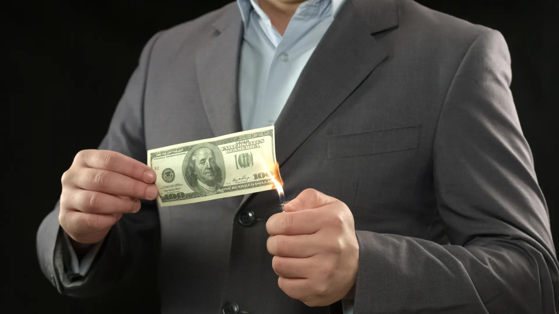 Man lighting a $100 bill with a lighter.